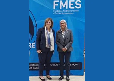 Deux participantes posant devant le mur de la Fondation méditerranéenne d’études stratégiques (FMES)