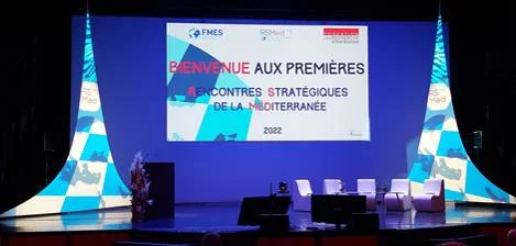 Scène des premières Rencontres stratégiques de la Méditerranée 2022 : écran de bienvenue FMES et fauteuils vides